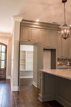 an empty kitchen with white cabinets and wood floors