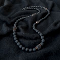 A grounding stone, Onyx is believed to absorb negative energies, alleviates worries and tensions, and eliminates confusion. It helps in being structured and letting go of unhappy thoughts. There is 1 accent cube Lava Stone bead, which is repeated multiple times for Balance. A grounding stone, Lava Stone is believed to provide stability during times of change and encourages strength and courage. It promotes change where needed for behavioral issues and enhances fertility. This necklace has an ela Men Necklace With Stone, Men’s Necklace Layering, Men Crystal Necklace, Black Necklace Men, Mens Stone Necklace, Men’s Beaded Necklace, Necklace For Men Aesthetic, Men Boho, Mens Necklaces