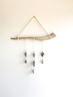 a piece of driftwood hanging on a wall with beads and wood sticks attached to it