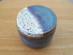 a small blue and white bowl sitting on top of a wooden table next to a cup