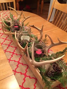 a wooden tray with candles and deer antlers on top of a dining room table