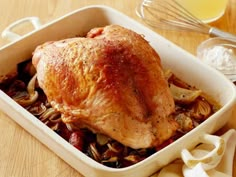 a close up of a chicken in a casserole dish on a wooden table