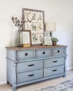 an old dresser is painted blue and has pictures on it with flowers in vases