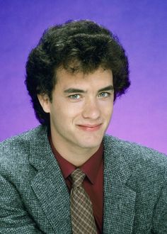 a young man in a suit and tie posing for a photo against a purple background