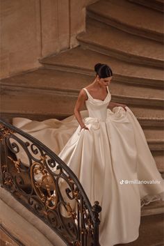 a woman in a wedding dress walking down some stairs