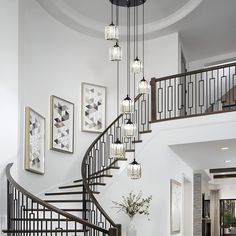 a spiral staircase with chandelier and pictures on the wall