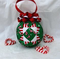 a christmas ornament with candy canes on the side and a bow around it