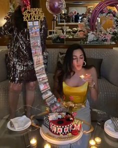 a woman sitting on a couch with a cake in front of her and candles around her