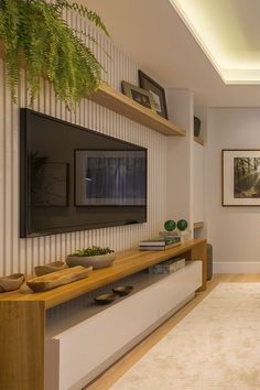 a living room with a large flat screen tv mounted on the wall next to a plant