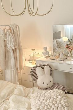 a bedroom with a white bed, dressing table and mirror on the wall next to it