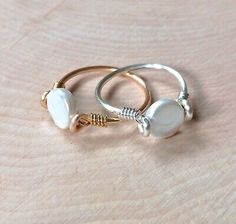 two rings with pearls on them sitting on top of a wooden table