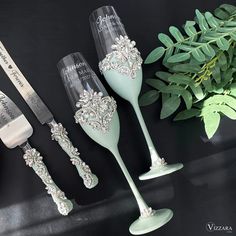 three wine glasses and two silverware are sitting on a table next to greenery