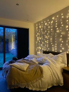 a bedroom with lights on the wall and a bed in front of a sliding glass door