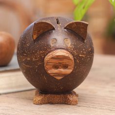 a wooden pig figurine sitting on top of a table next to a potted plant