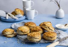 some biscuits are sitting on a plate next to cups and spoons