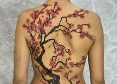 the back of a woman's body is decorated with cherry blossom blossoms and branches