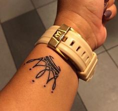 a person with a tattoo on their arm holding onto a wrist watch and looking at the camera