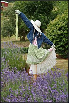 a woman in a dress and hat is standing in the middle of lavenders with her arms outstretched