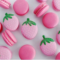 pink macaroons and donuts with green leaves on them are arranged in the shape of strawberrys