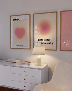 a white dresser topped with a lamp next to two framed pictures