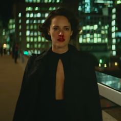 a woman with red lipstick on her lips standing in front of a cityscape