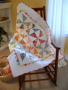 a chair with a quilt on it and a basket in front of the chair next to it