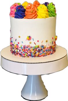 a white cake with sprinkles and rainbow colored frosting on it's side