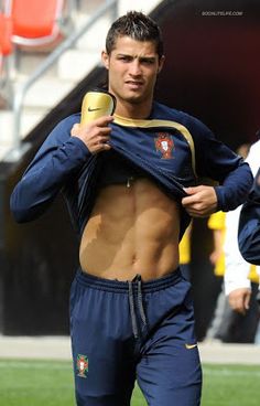 a shirtless soccer player holding a cup in his right hand while standing on the field