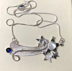 "I fabricated a Shooting Star necklace design in sterling silver with a Moonstone and Sapphire. If you prefer different gems, please let me know! You can select your gemstone choice from the drop down menu in the listing! The piece comes with a 16 inch chain at 1.2mm thick and with a lobster claw for security. The pendant is approximately 2 and 1/4 inches in size and attached is a 16\" box chain. Everything is handmade, by me, per order and is in sterling silver. Nothing is mass-produced! There Sterling Silver Celestial Necklace With Polished Finish, Sterling Silver Star Gemstone Jewelry, Celestial Silver Necklace With Gemstone, Silver Star Of David Necklace With Gemstone, Celestial Silver Gemstone Necklace, Sterling Silver Star Necklace With Gemstone, Silver Star Necklaces With Birthstone, Silver Star Of David Birthstone Jewelry, Silver Star Of David Jewelry With Birthstone