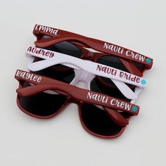 three pairs of sunglasses with name tags attached to the lenses, sitting on top of each other