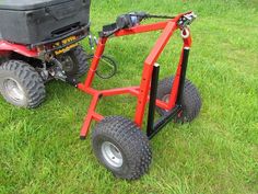 a red cart sitting on top of a lush green field next to a black box