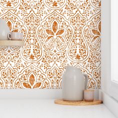 a red and gold wallpaper with some white vases on the counter next to it