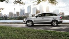 a silver car is parked in front of a cityscape with the sun shining on it