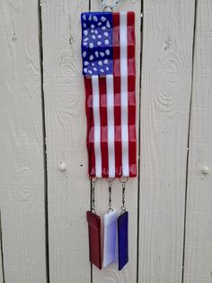 a red, white and blue american flag hanging on a wooden fence with two bookmarks attached to it