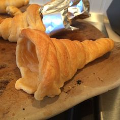 croissants wrapped in aluminum foil sitting on a cutting board