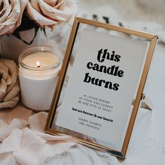 there is a candle and some flowers on the table with a sign that says, this candle burns