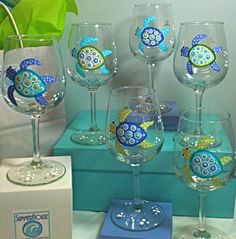 four wine glasses with sea animals painted on them are sitting next to a blue box