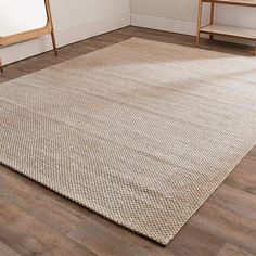 a large rug in the corner of a room with two wooden chairs and a mirror