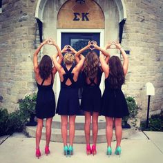 four women standing in front of a building with their hands on their hipss and wearing high heels