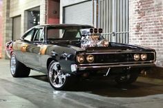 an old muscle car parked in front of a brick building