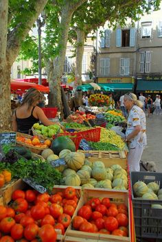 people shopping at an open air market with lots of fresh fruits and vegetables on display