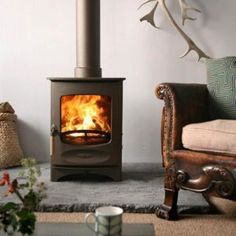 a wood burning stove in a living room next to a chair and coffee cup on the floor