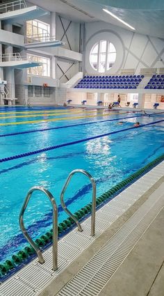 an indoor swimming pool with stairs leading up to the water and people in the distance