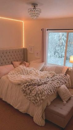 a bedroom with a large bed covered in blankets and pillows next to a big window