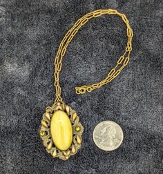 Get ready to dazzle with this fabulous vintage pendant necklace! Featuring a striking yellow stone set in an ornate frame, this beauty is sure to make you feel like a retro queen. The delicate chain adds just the right touch of elegance to complete your look. Perfect for any occasion where you want to stand out and shine! Snap up this unique piece and add a burst of vintage charm to your jewelry collection today! Vintage Cabochon Pendant Necklace, Antique Gold Retro Jewelry For Vintage Collection, Retro Style Necklace With Large Pendant, Elegant Antique Gold Cabochon Necklace, Retro Gold Cameo Jewelry, Yellow Costume Jewelry Necklace For Formal Occasions, Yellow Costume Jewelry Necklace For Formal Events, Collectible Vintage Amber Jewelry, Vintage Amber Oval Pendant Jewelry