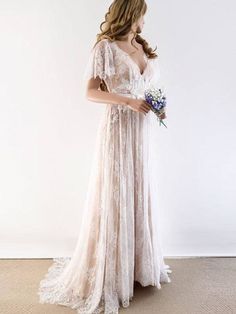 a woman in a wedding dress holding a flower bouquet and looking down at the floor