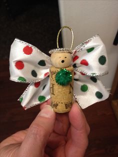 a hand holding a cork angel ornament with green and red dots on it