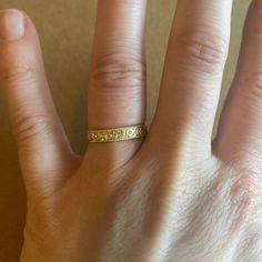 a person's hand with a gold ring on top of their thumb and fingers