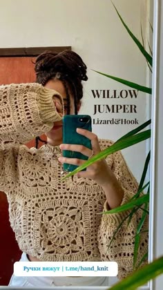 a woman taking a selfie in front of a mirror wearing a sweater and holding a cell phone