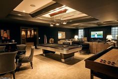 a living room with a pool table, couches and tables in it's center